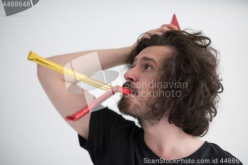 Image of Portrait of a man in party hat blowing in whistle