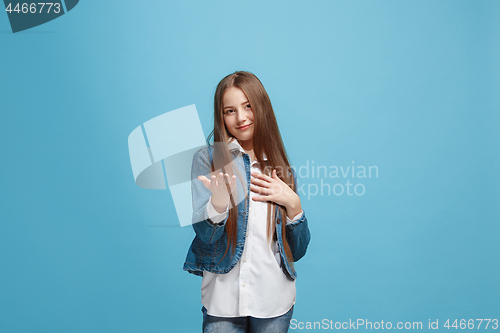 Image of The happy teen girl with phone standing and smiling against pink background.