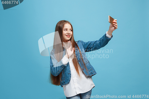 Image of The happy teen girl standing and smiling against pink background.