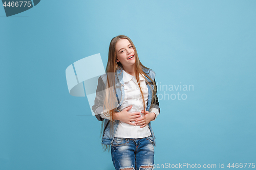 Image of The happy teen girl standing and smiling against pink background.
