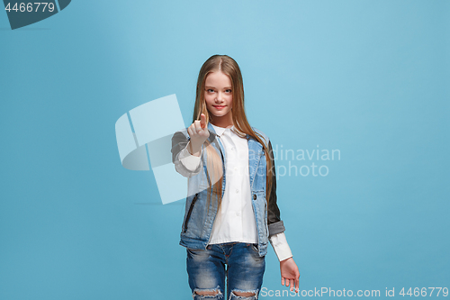 Image of The happy teen girl pointing to you, half length closeup portrait on blue background.