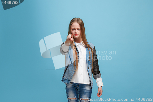 Image of The happy teen girl pointing to you, half length closeup portrait on blue background.