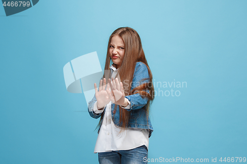 Image of Doubtful pensive teen girl rejecting something against blue background