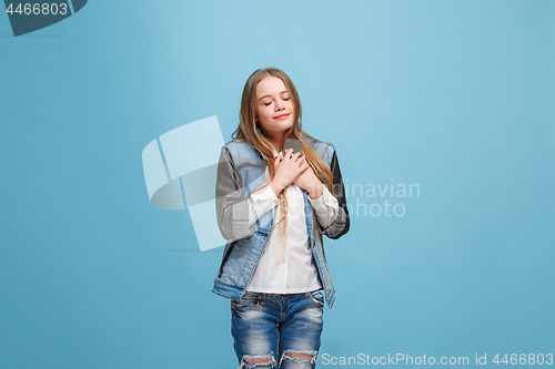 Image of The happy teen girl standing and smiling against pink background.