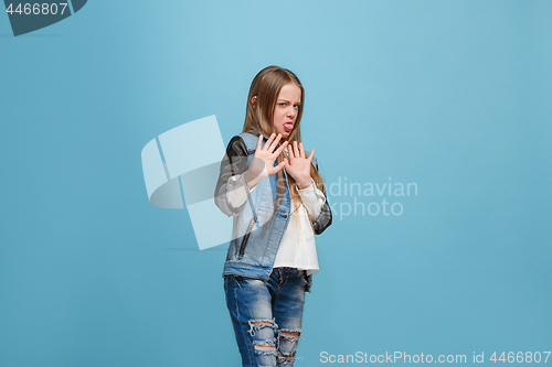 Image of Doubtful pensive teen girl rejecting something against blue background