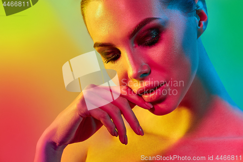 Image of High Fashion model woman in colorful bright lights posing in studio