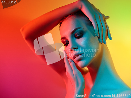 Image of High Fashion model woman in colorful bright lights posing in studio