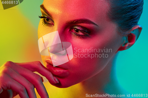 Image of High Fashion model woman in colorful bright lights posing in studio