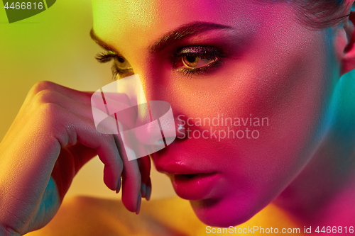 Image of High Fashion model woman in colorful bright lights posing in studio