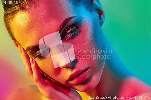 Image of High Fashion model woman in colorful bright lights posing in studio