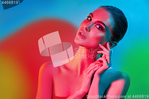 Image of High Fashion model woman in colorful bright lights posing in studio