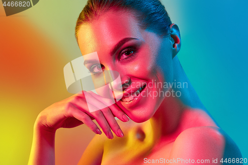 Image of High Fashion model woman in colorful bright lights posing in studio