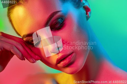 Image of High Fashion model woman in colorful bright lights posing in studio