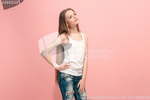Image of The happy teen girl standing and smiling against pink background.