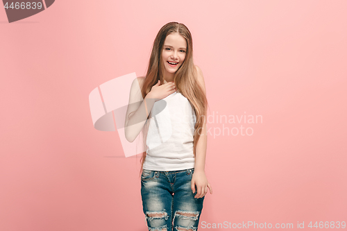 Image of The happy teen girl standing and smiling against pink background.