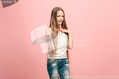 Image of The happy teen girl standing and smiling against pink background.