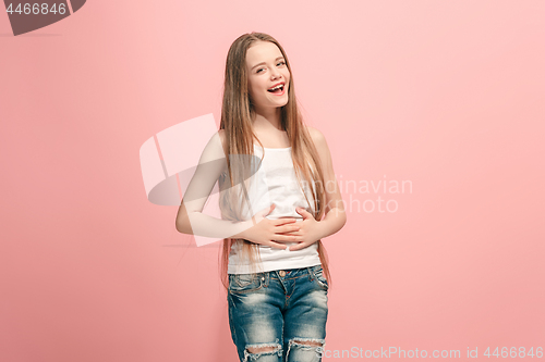 Image of The happy teen girl standing and smiling against pink background.