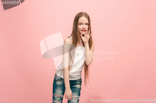 Image of The young teen girl whispering a secret behind her hand over blue background