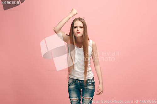 Image of Portrait of angry teen girl on a pink studio background