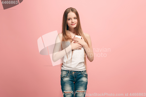 Image of The happy teen girl standing and smiling against pink background.