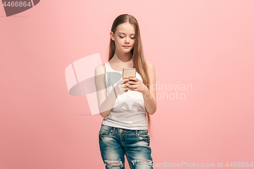 Image of The happy teen girl standing and smiling against pink background.