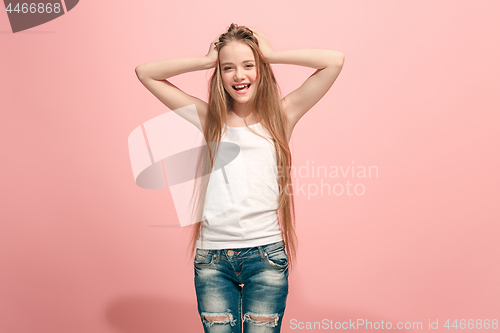 Image of The happy teen girl standing and smiling against pink background.