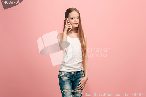 Image of The happy teen girl standing and smiling against pink background.