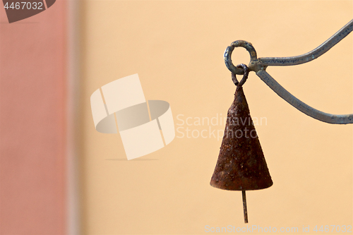 Image of old rusty cone shaped bell hanging against blank wall
