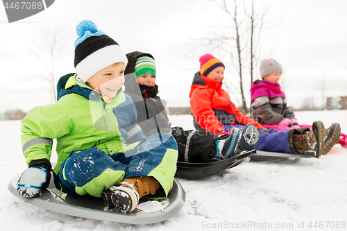 Image of happy little kids sliding on sleds in winter