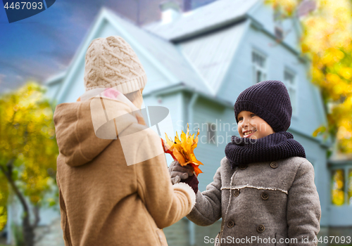 Image of kids with autumn maple leaves over house outdoors