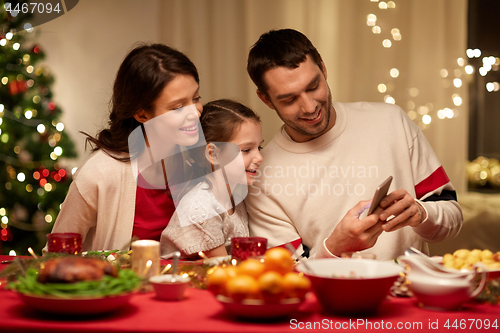 Image of family with smartphone having christmas dinner