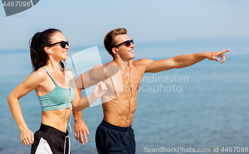 Image of couple with earphones running along on beach