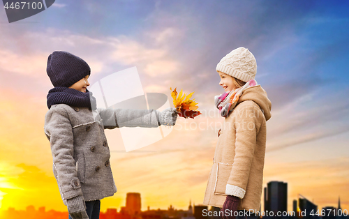 Image of kids with autumn leaves over tallinn city sunset