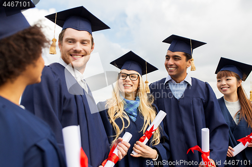 Image of happy students in mortar boards with diplomas