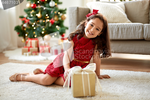 Image of happy girl with christmas gift at home