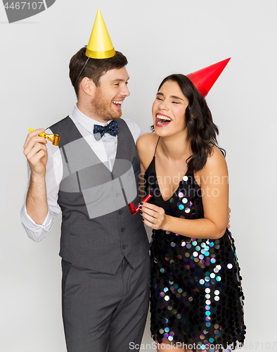 Image of happy couple with party blowers having fun