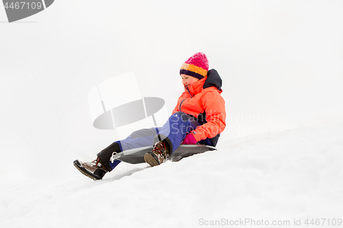 Image of happy little girl sliding down on sled in winter