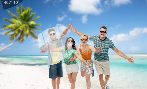 Image of friends in sunglasses having fun on tropical beach