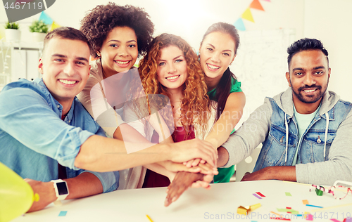 Image of happy business team at office party holding hands