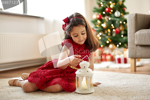 Image of little girl with lantern at home on christmas
