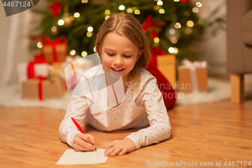 Image of smiling girl writing christmas wish list at home