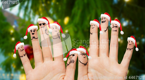 Image of ten fingers in santa hats over christmas tree