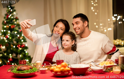 Image of happy family taking selfie at christmas dinner