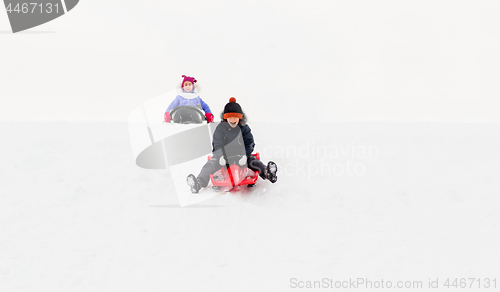 Image of happy kids sliding on sleds down hill in winter