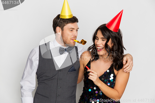 Image of happy couple with party blowers having fun