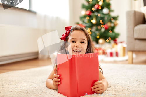 Image of happy girl reading book at home on christmas