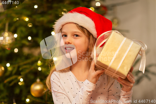 Image of smiling girl in santa hat with christmas gift