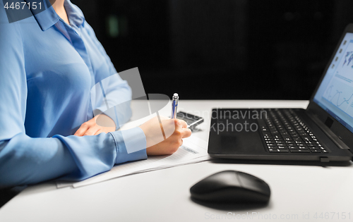 Image of businesswoman with papers working at night office