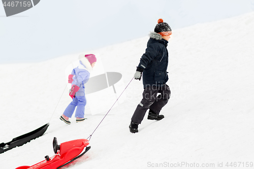 Image of kids with sleds climbing snow hill in winter