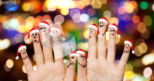 Image of close up of ten fingers in santa hats over lights